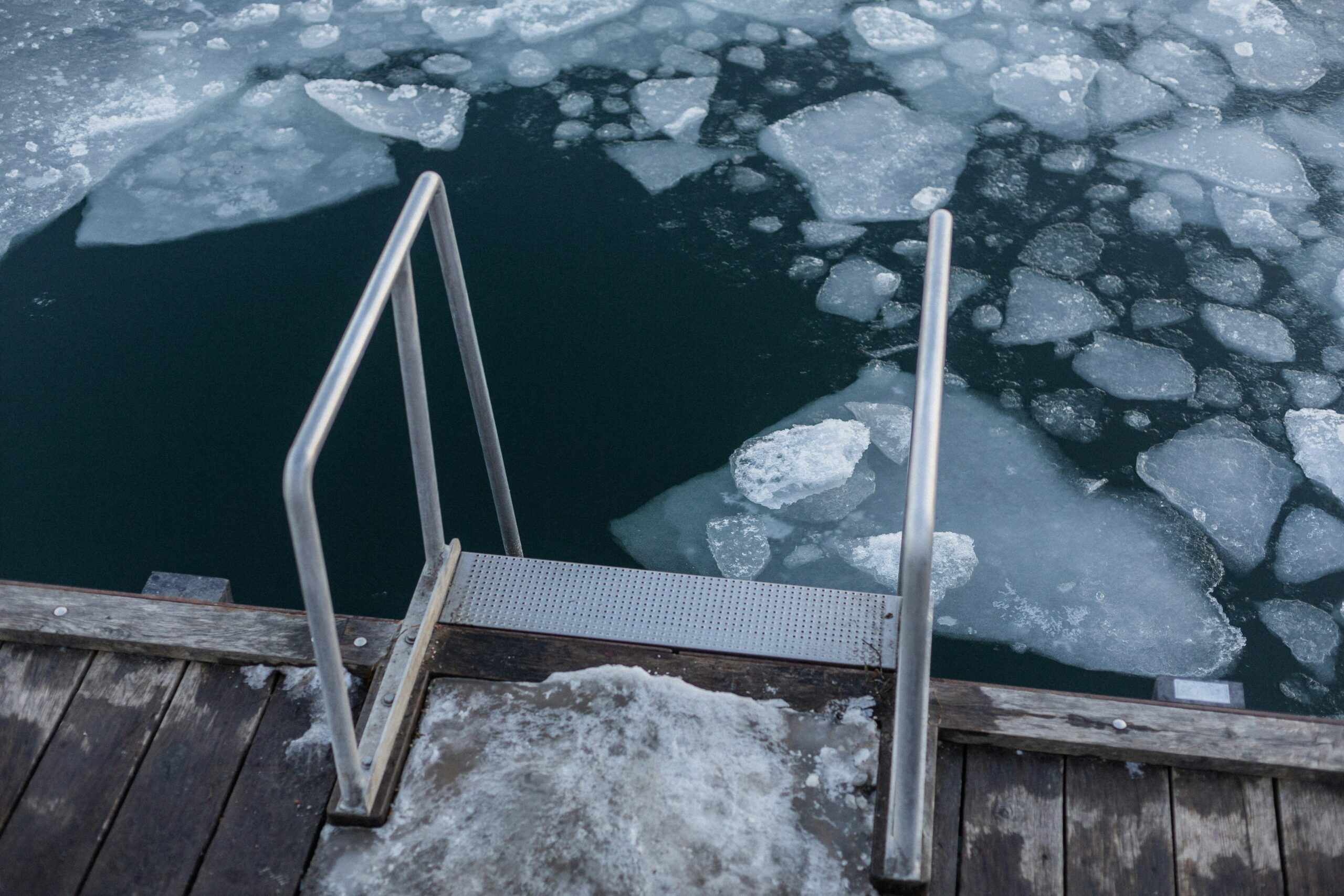 Schwimmstelle für Eisbaden in einem gefrorenen See, umgeben von Schnee und Eis mit klaren winterlichen Bedingungen, ideal für Winterwellness und gesundheitsfördernde Kälte-Therapie.